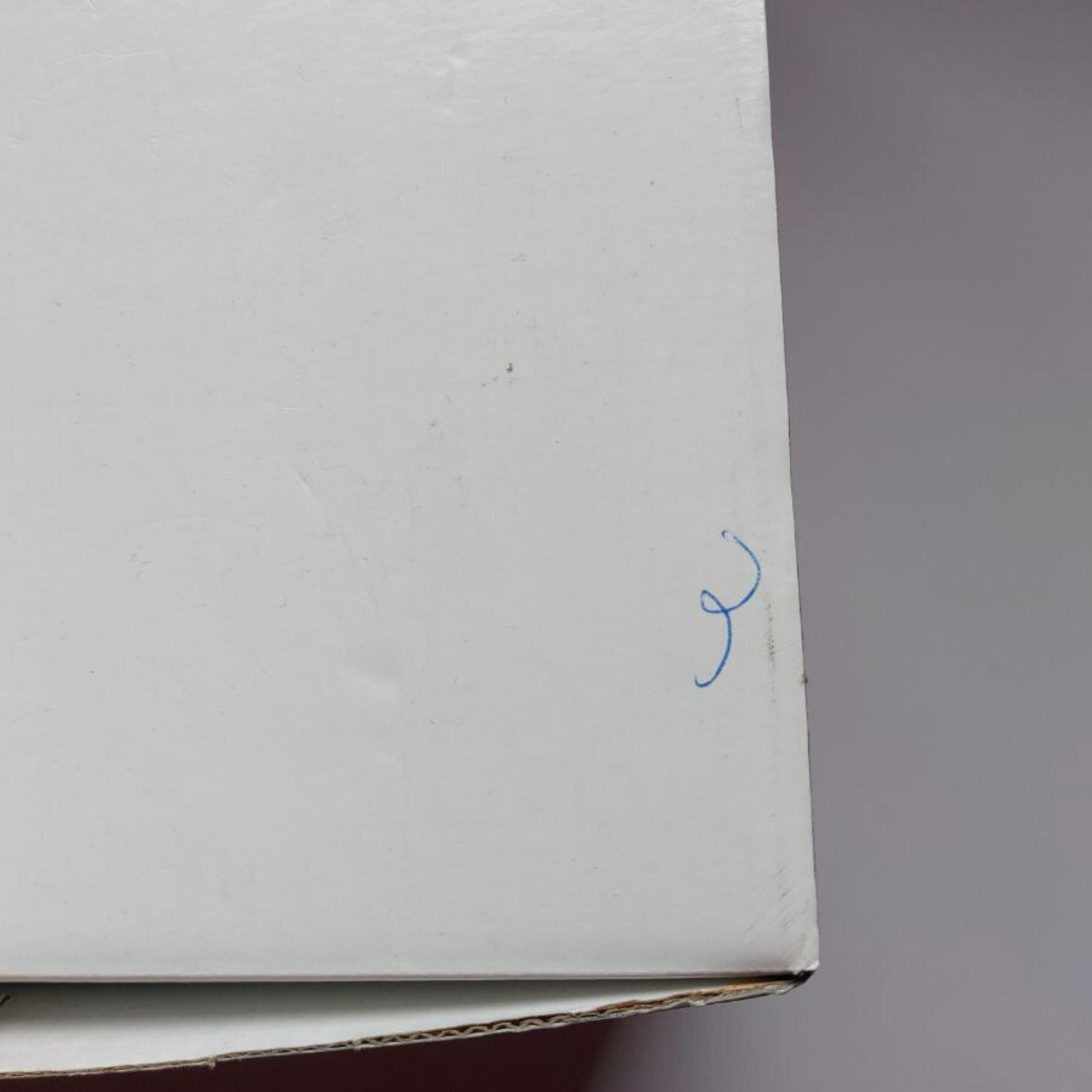 White cardboard box corner with a blue mark on a gray background