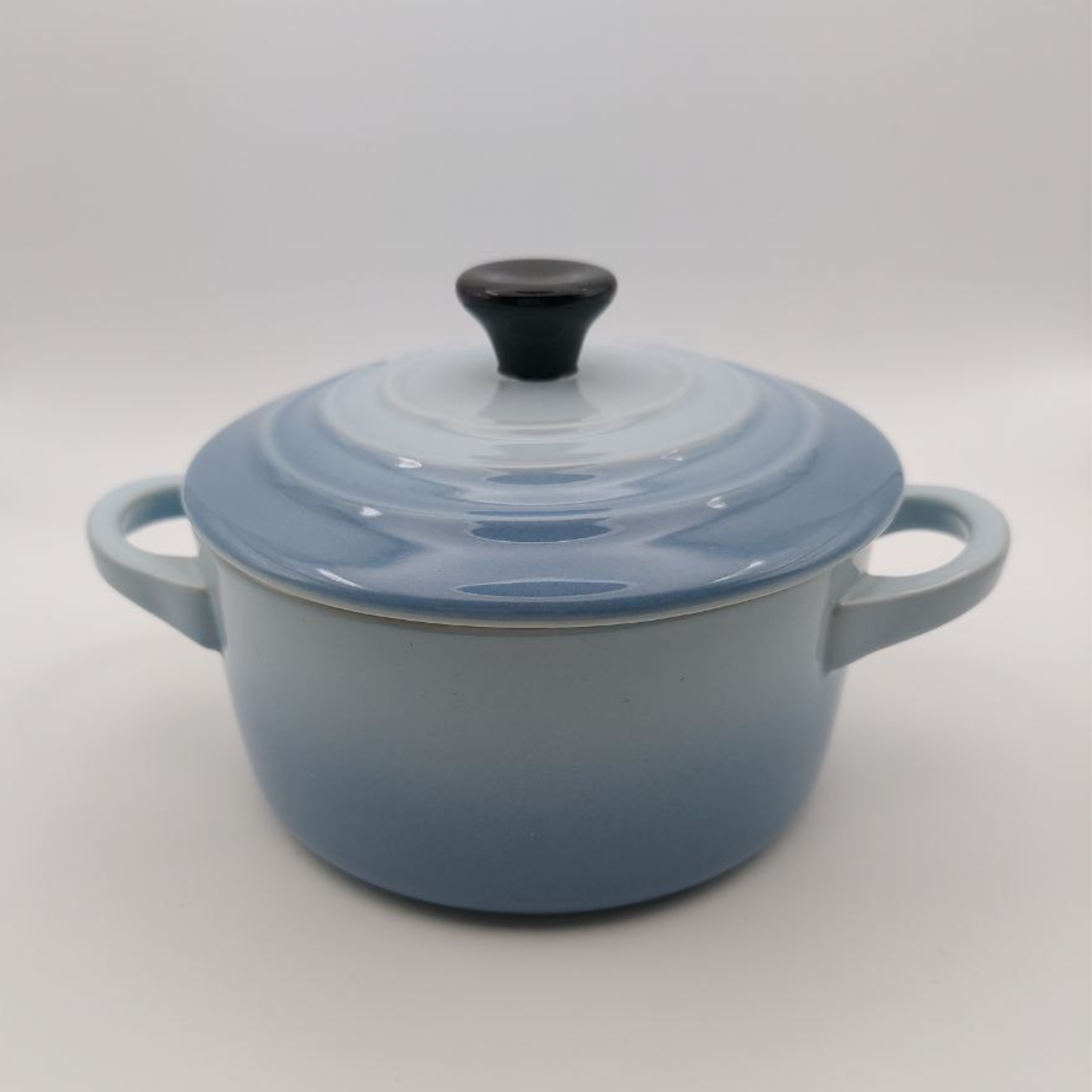 Blue enameled Le Creuset stoneware pot with lid on a white background