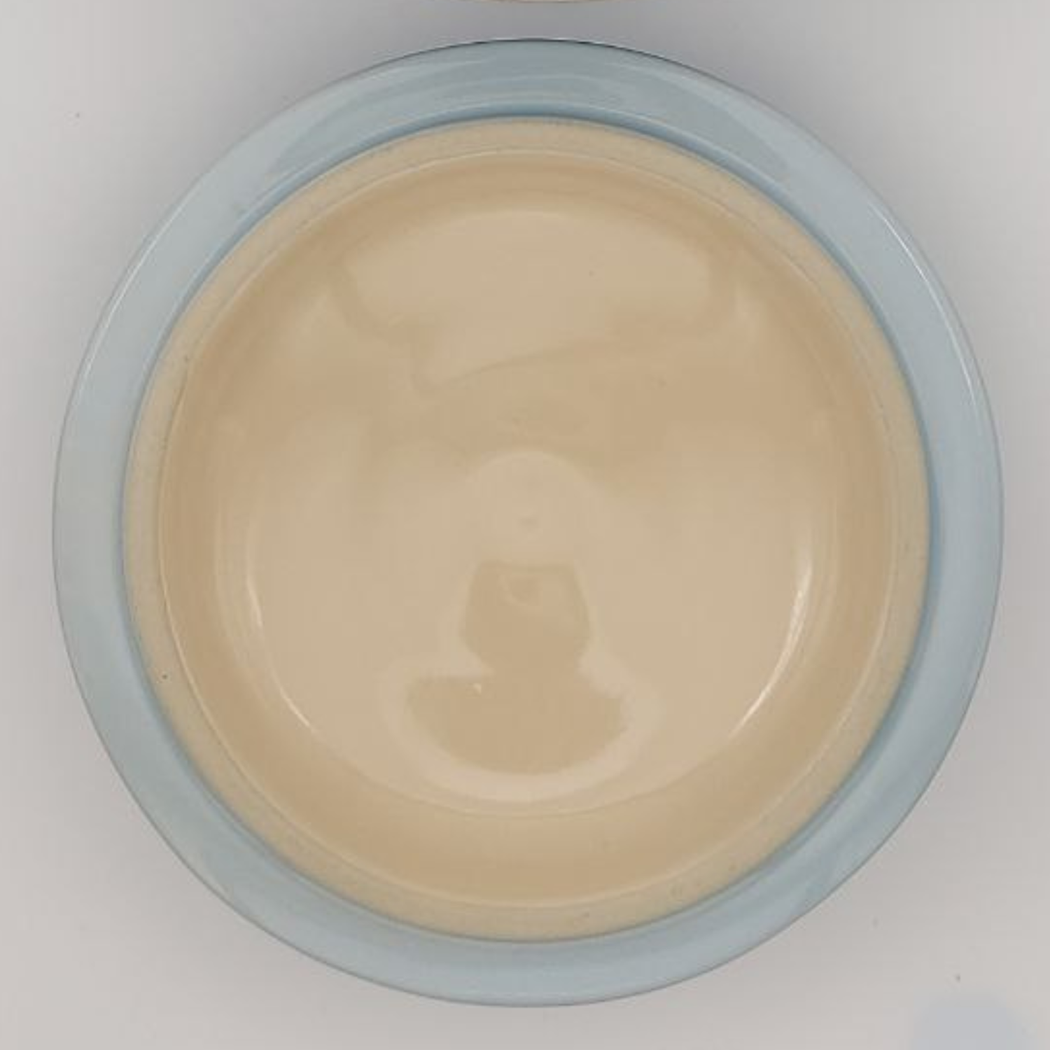 Beige cooking pot lid with blue rim on a white background