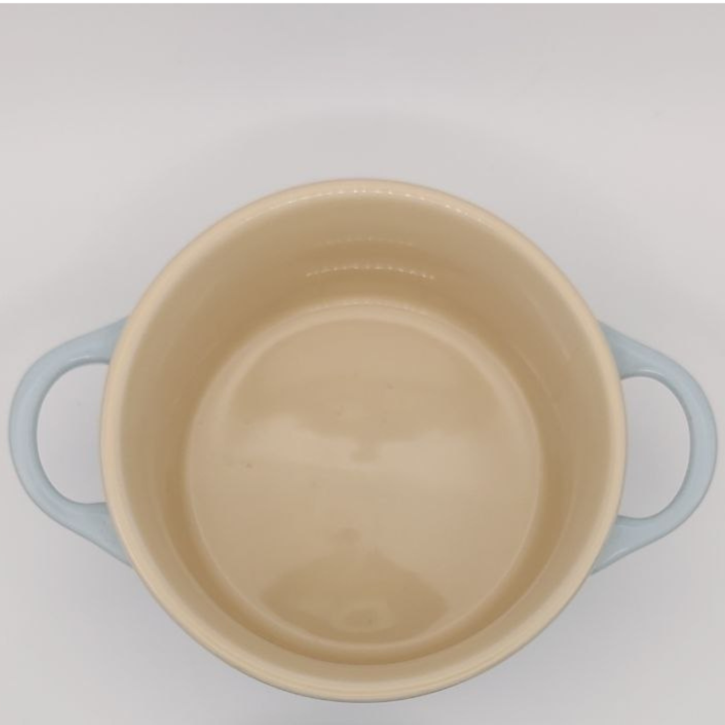 Beige pot with blue handles on a light grey background