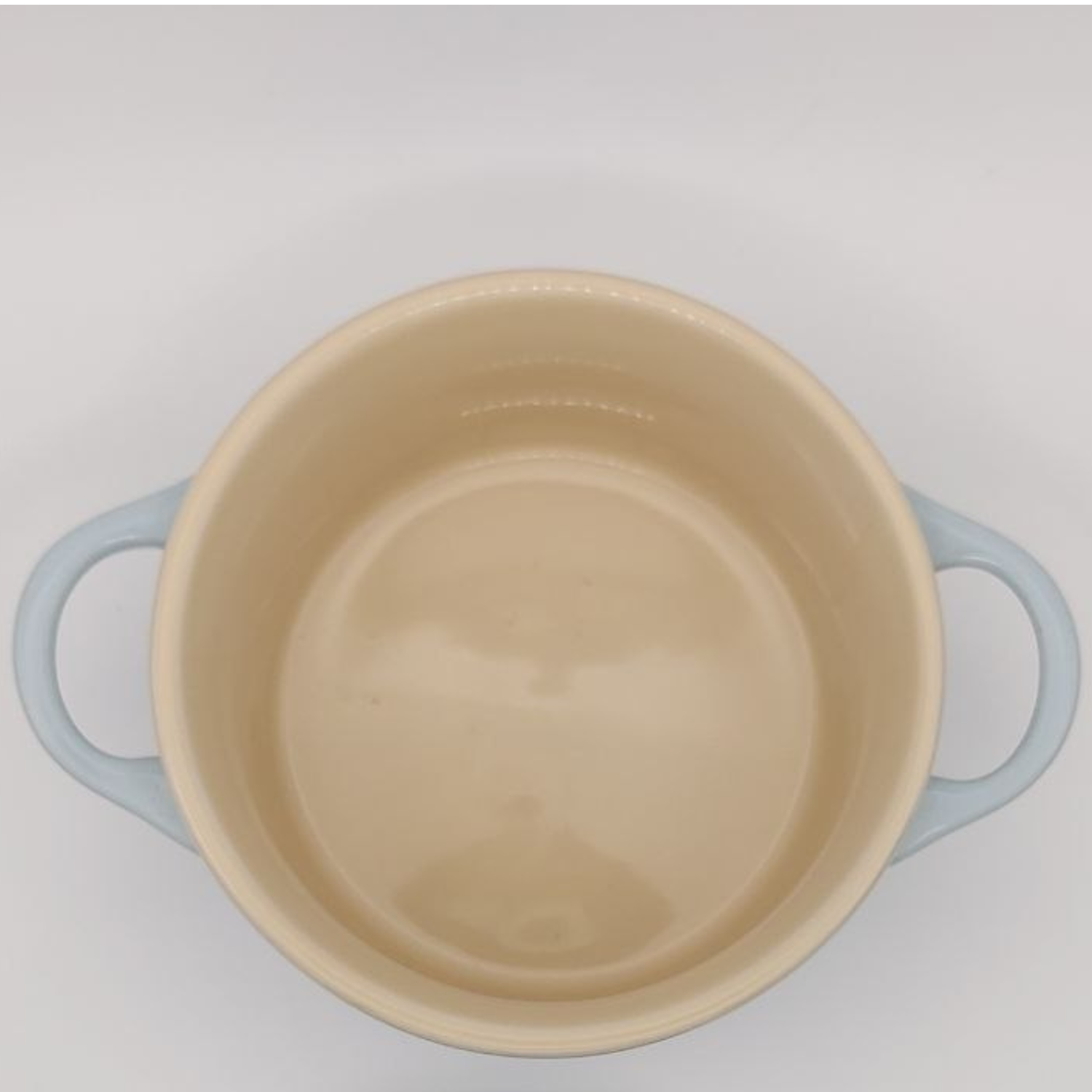 Beige pot with blue handles on a light grey background