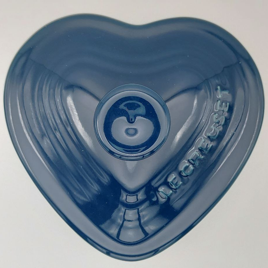 Heart-shaped blue container with a brand logo on a light grey background