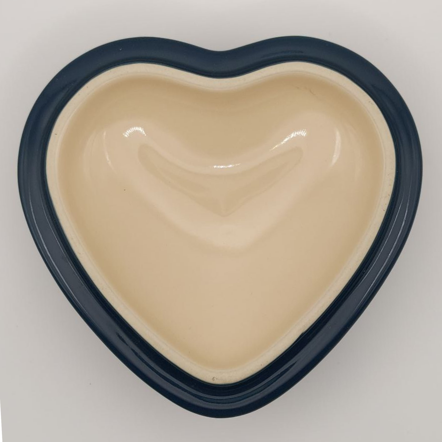 Heart-shaped lid with beige interior and navy exterior on a light grey background