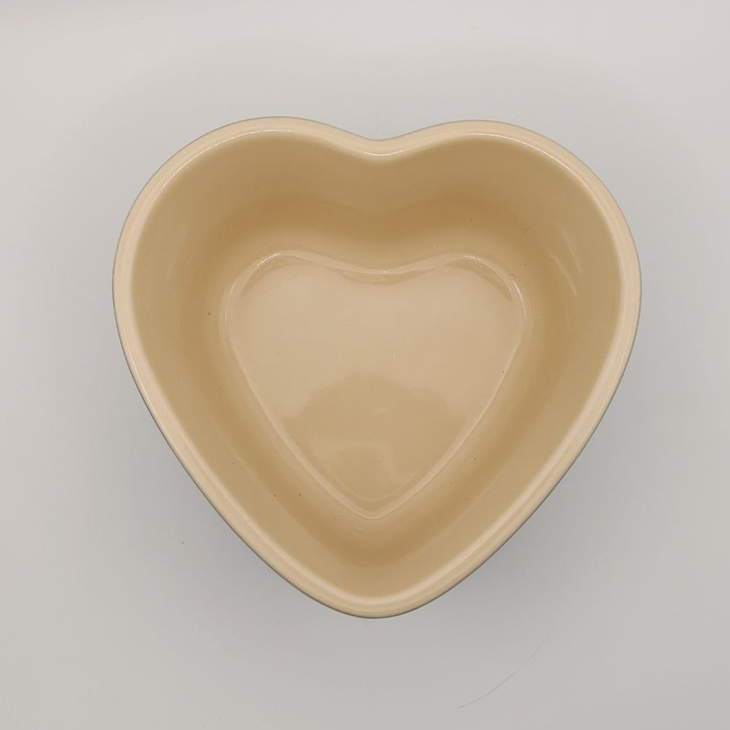 Heart-shaped beige bowl on a light grey background