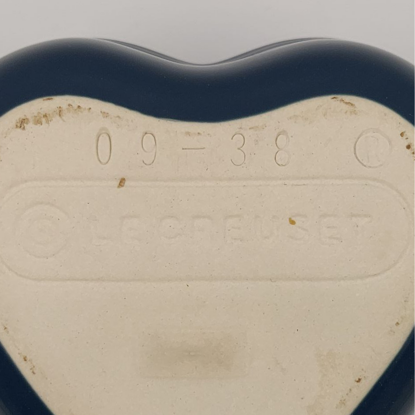 Heart-shaped object with embossed text on a plain background