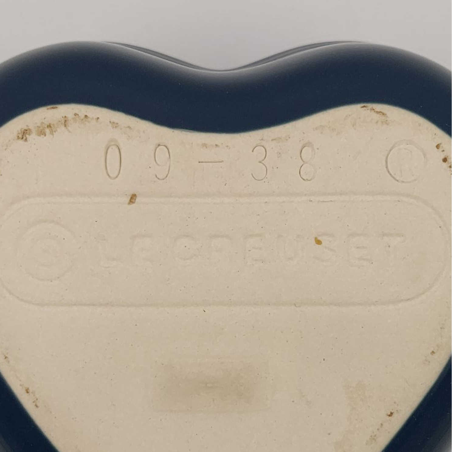 Heart-shaped object with embossed text on a plain background