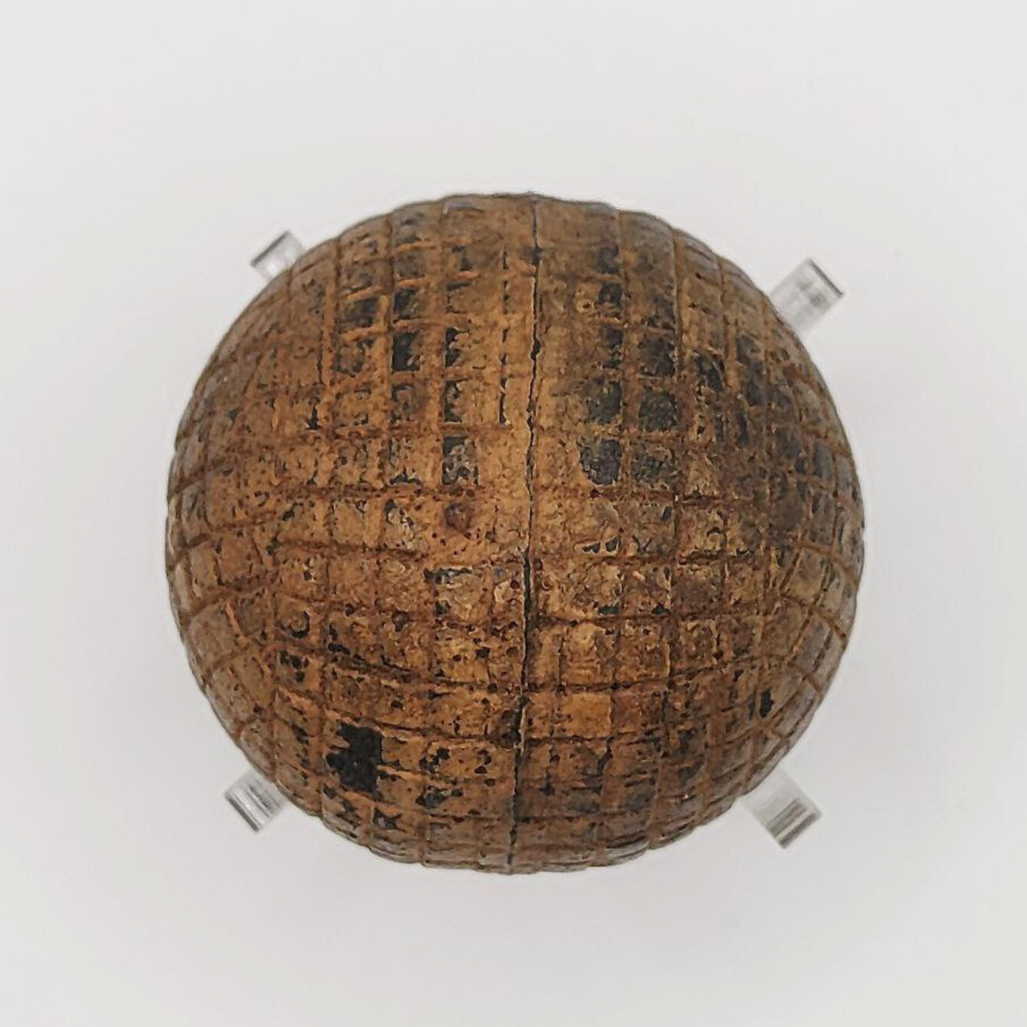 An old line-cut gutta percha golf ball on a white background