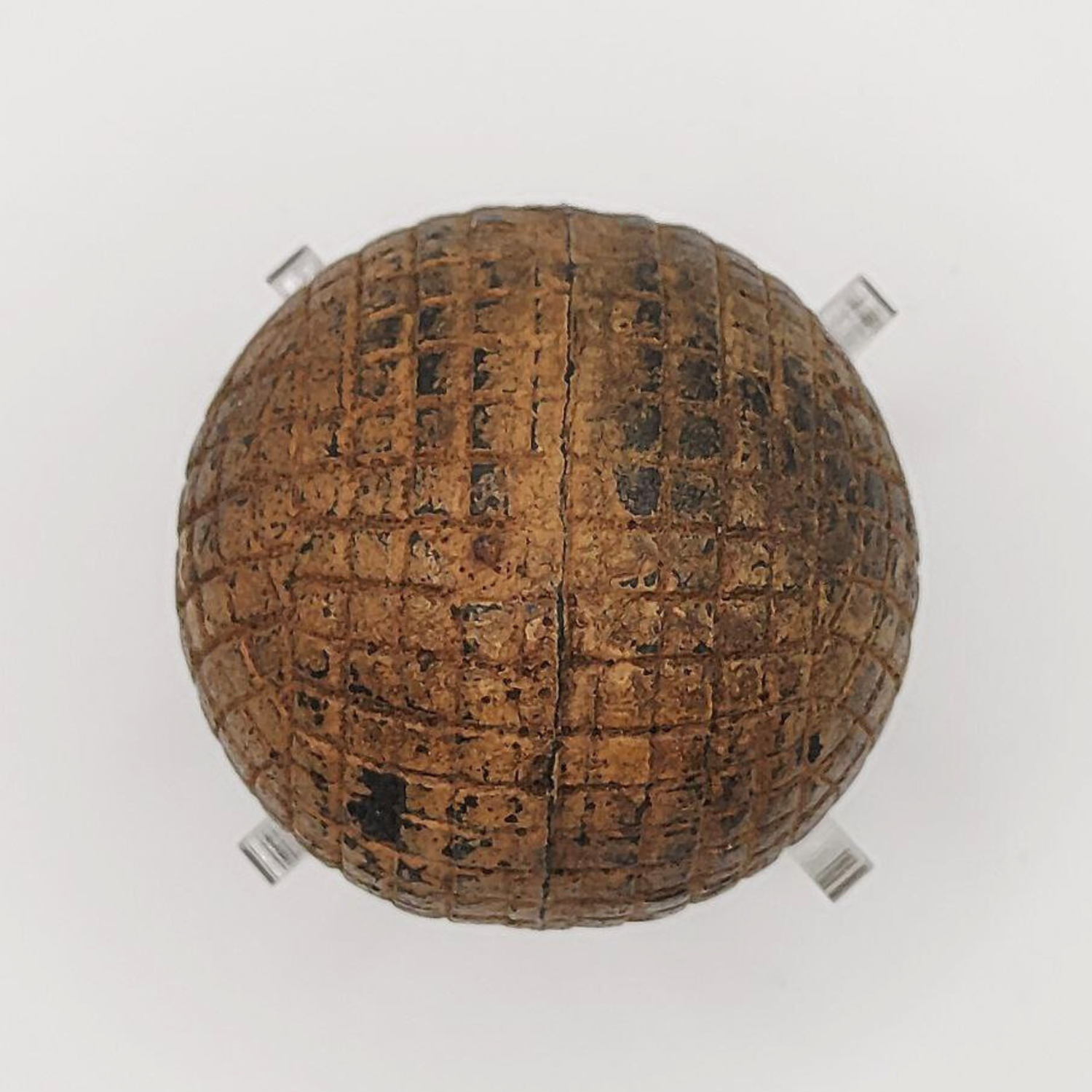 An old line-cut gutta percha golf ball on a white background