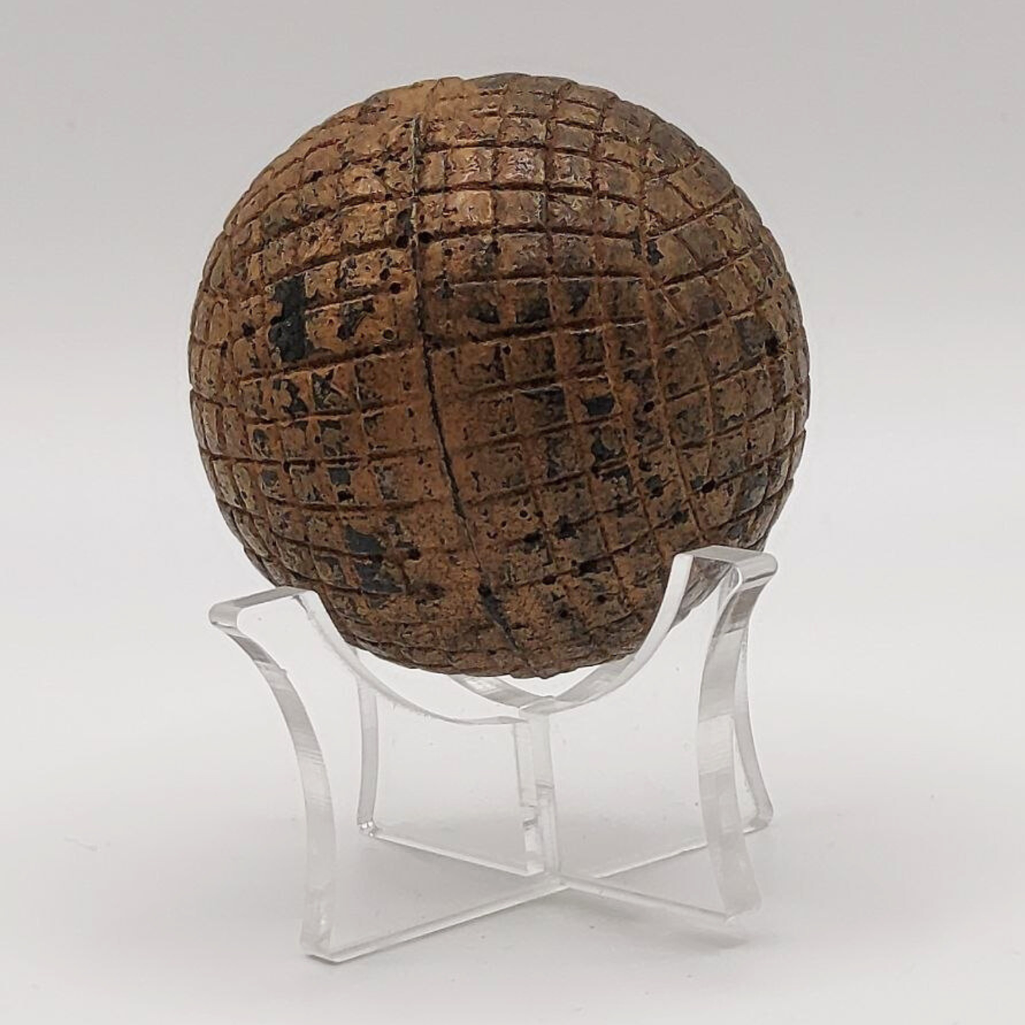 Antique golf ball on a stand against a white background