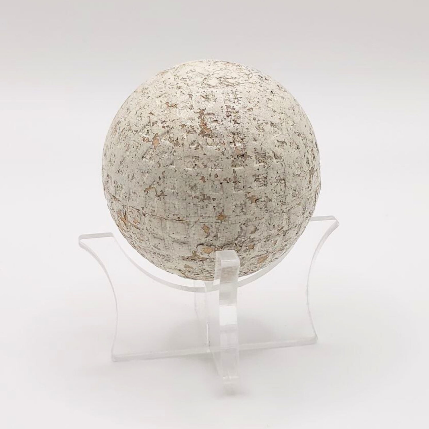 A vintage white golf ball on a plastic stand. 