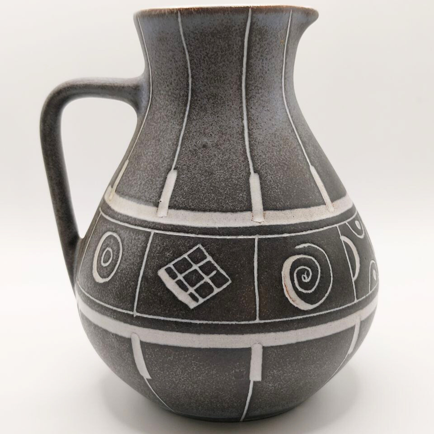 Grey ceramic jug with geometric patterns on a white background