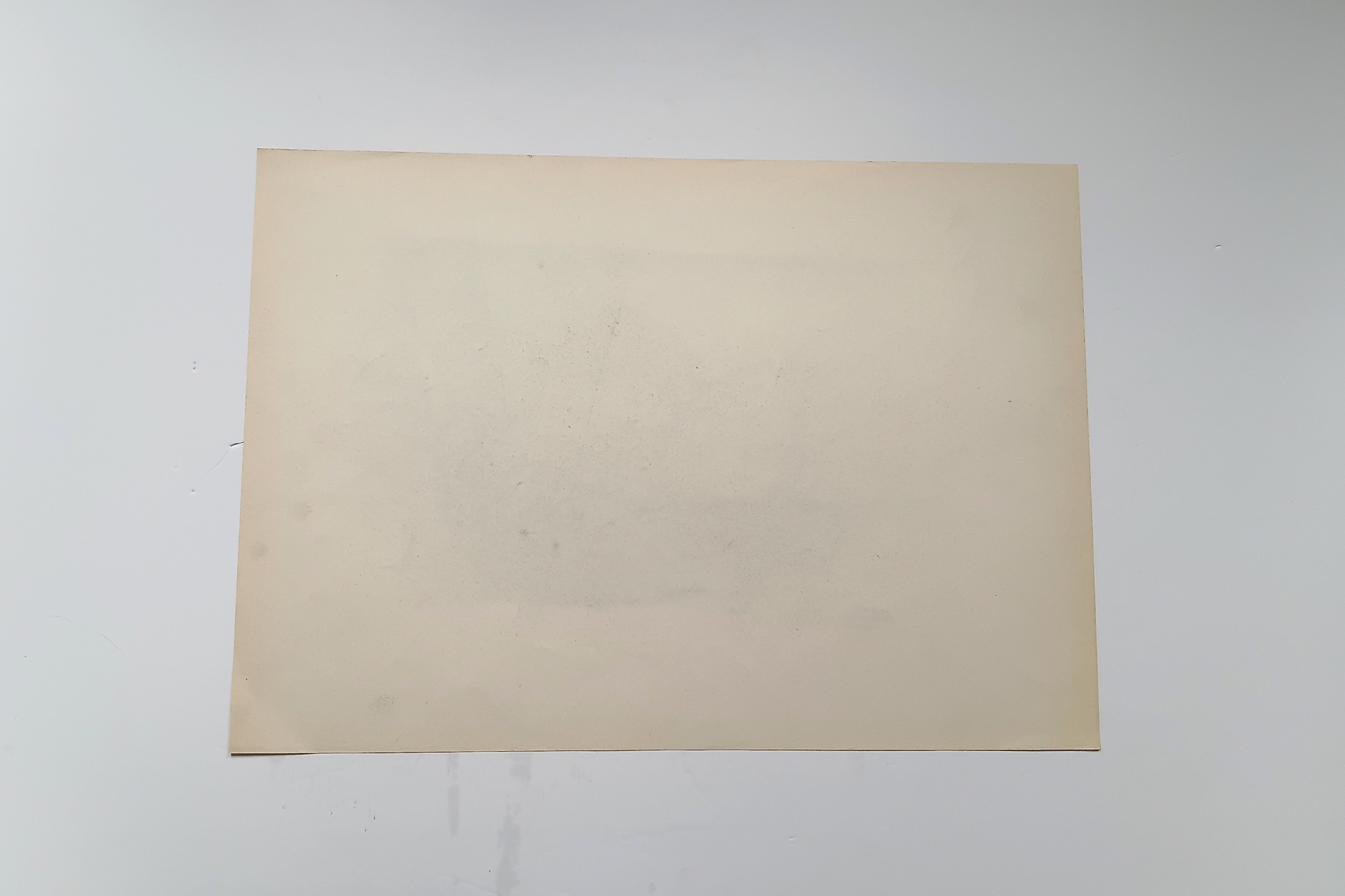 A blank, light beige rectangular sheet of paper or cardstock centered on a plain white background.