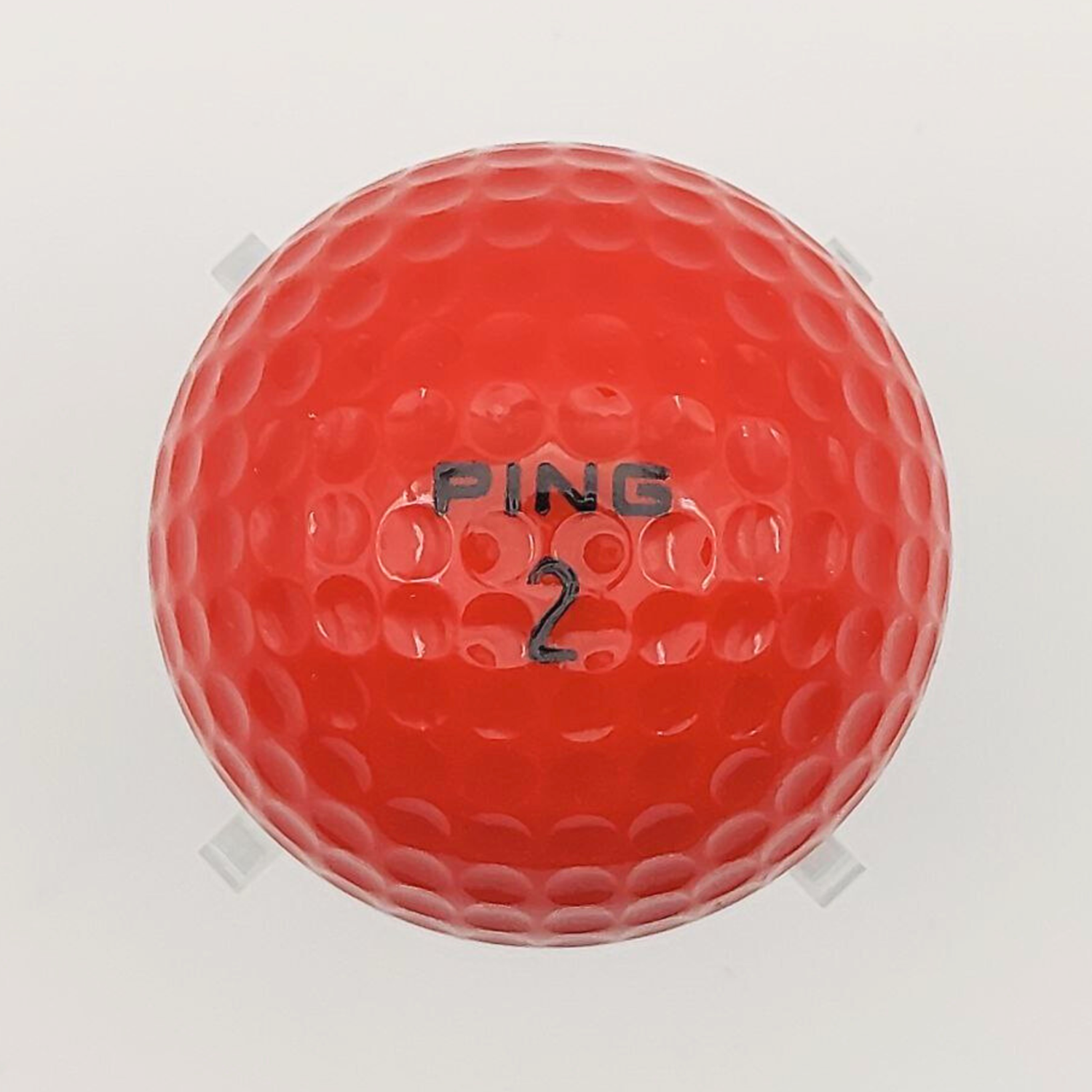 Orange golf ball with 'PING' branding and the number "2" on a white background