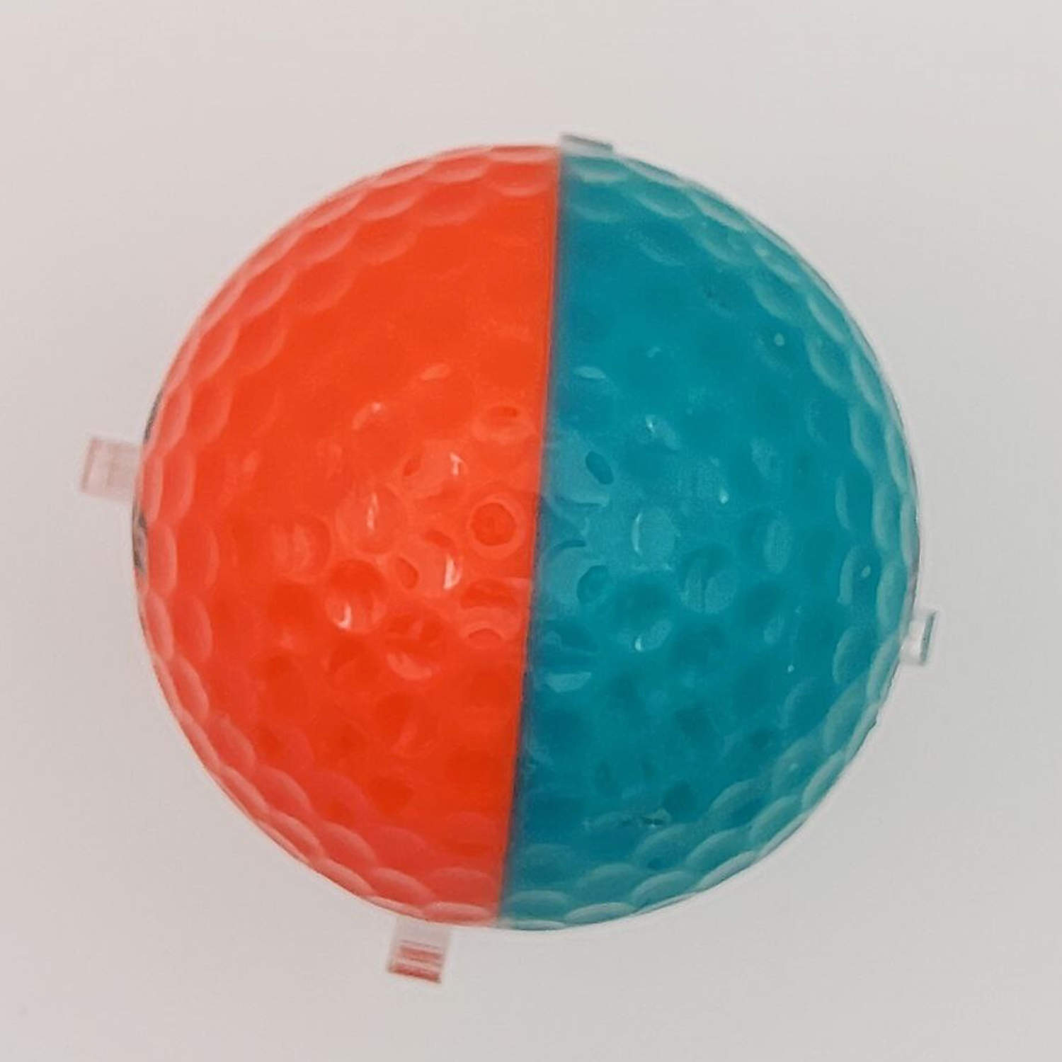 An orange and teal golf ball set against a white background. 