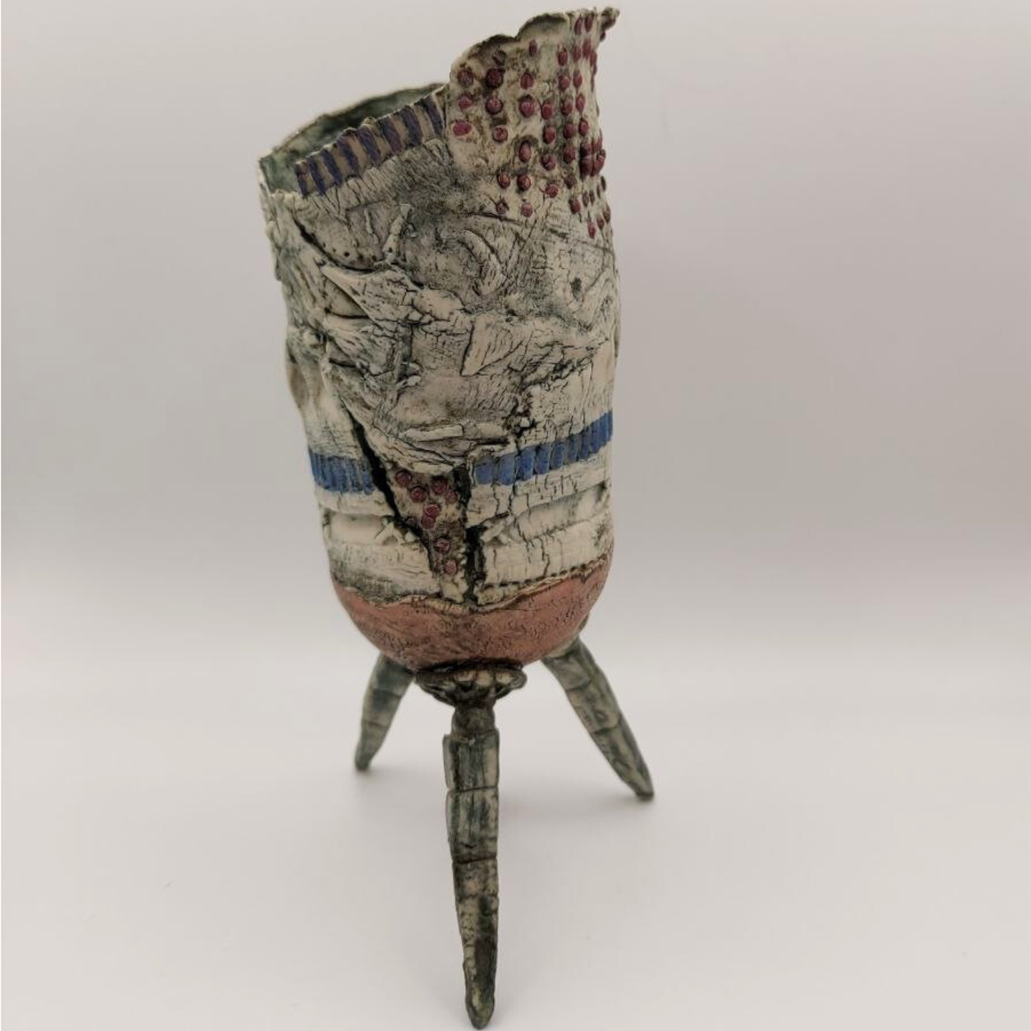 Abstract vase on a tripod base against a grey backdrop