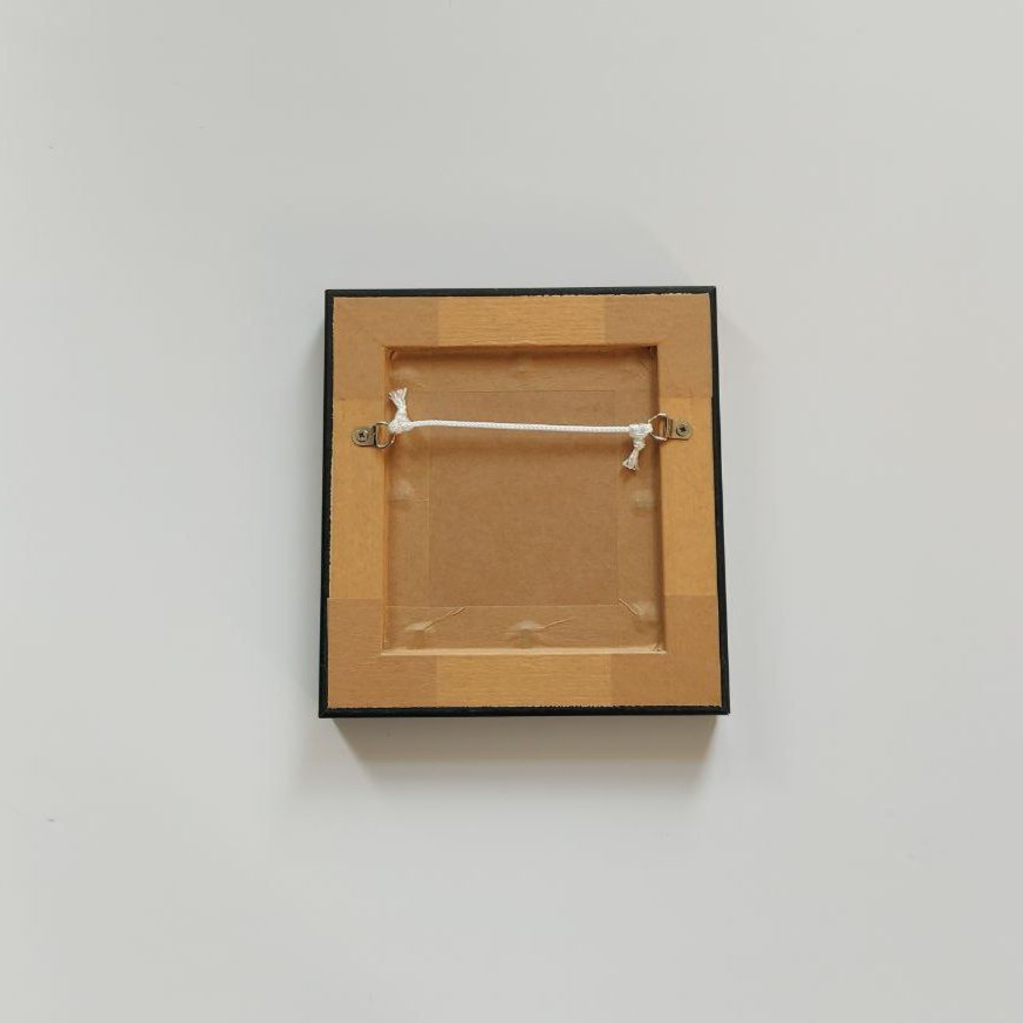 Wooden picture frame with a black border on a light gray background