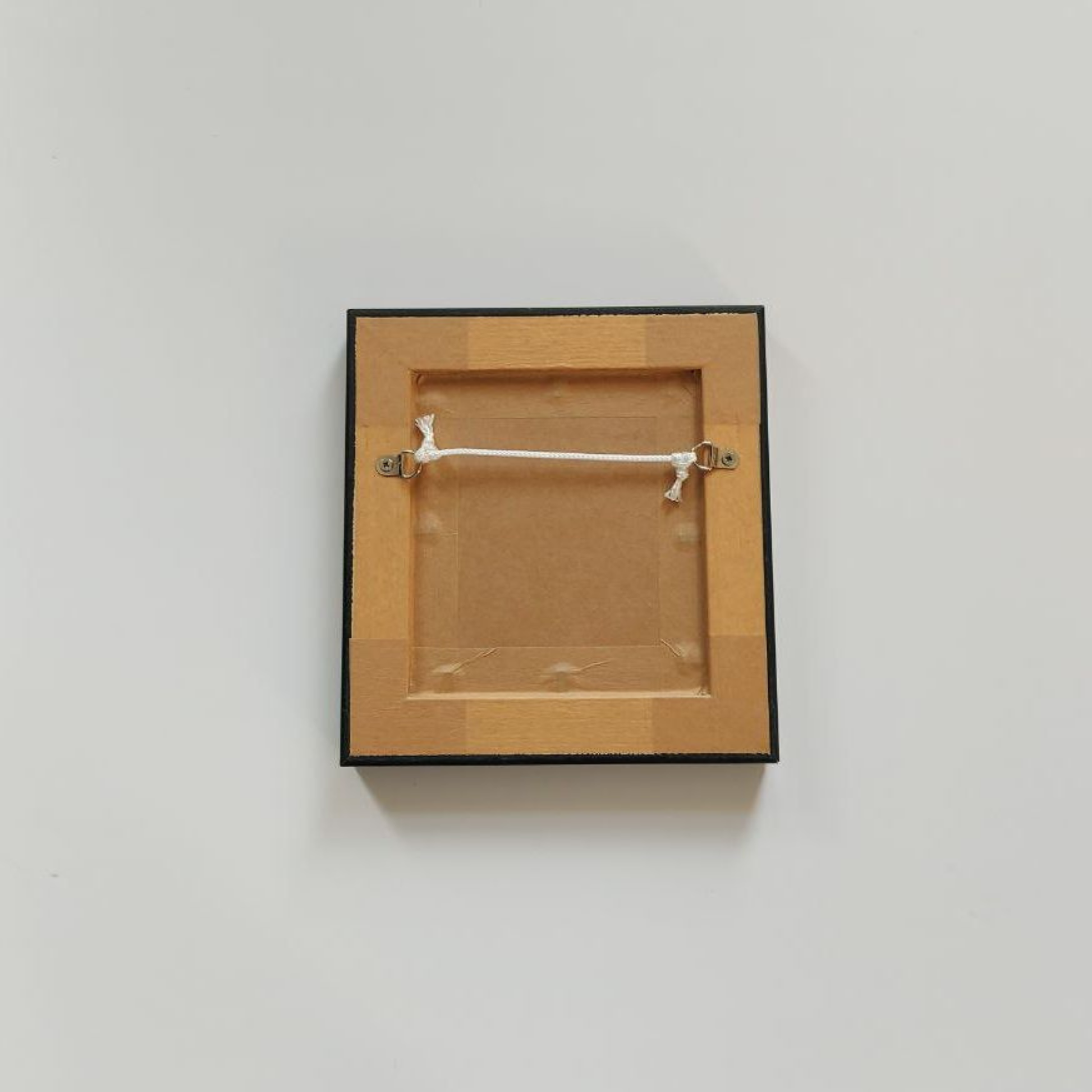 Wooden picture frame with a black border on a light gray background
