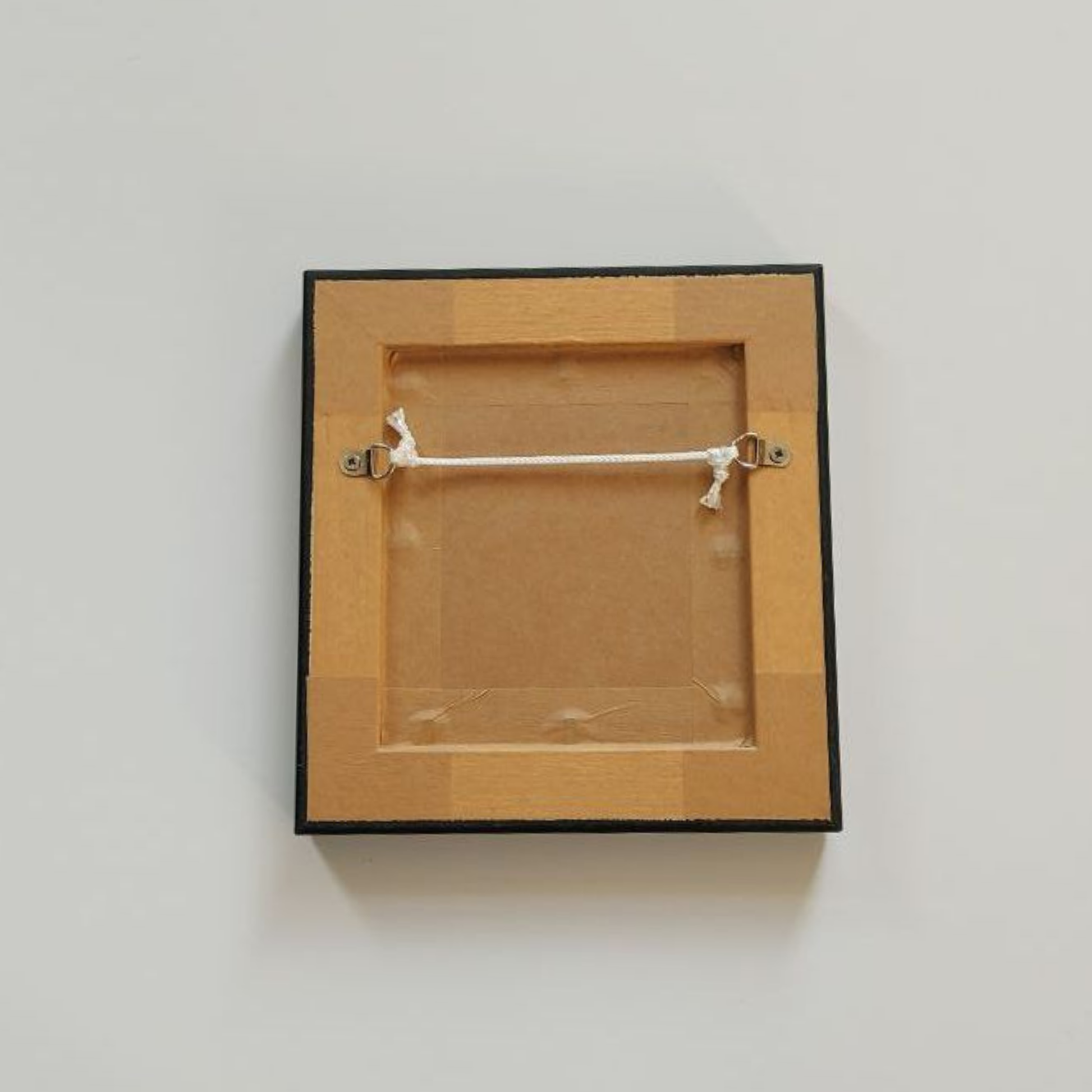 Wooden picture frame with a white string on a light gray background
