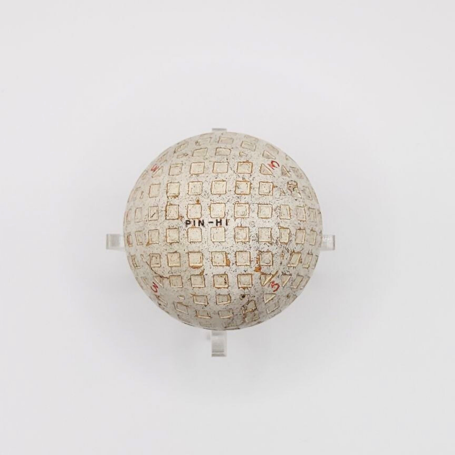 A vintage Pin-Hi golf ball on a plastic stand against a white background. 