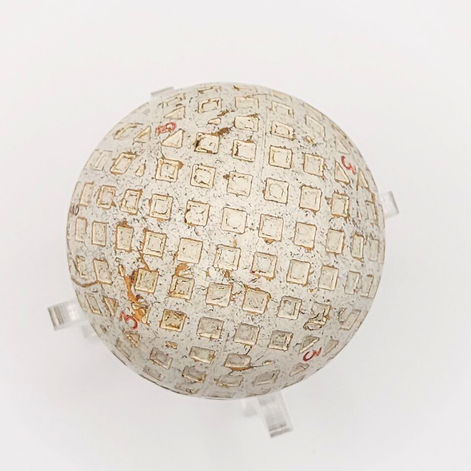 A Scottish Pin-Hi golf ball on a plastic stand against a white background. 