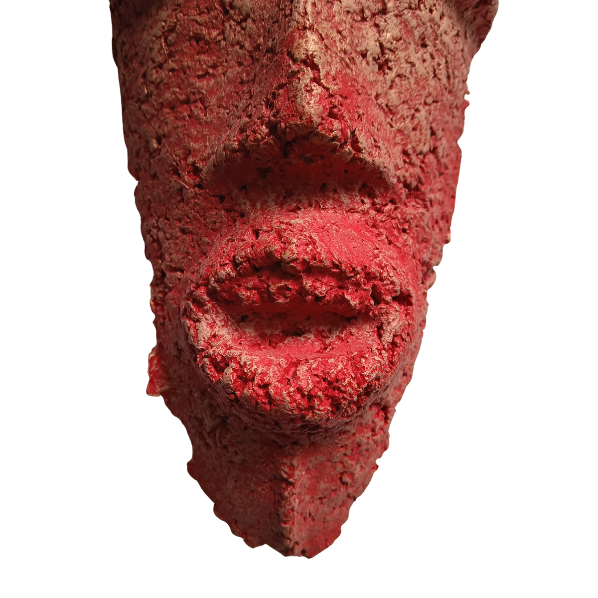 A close-up of a textured red sculpture or mask depicting a face, isolated on a white background.