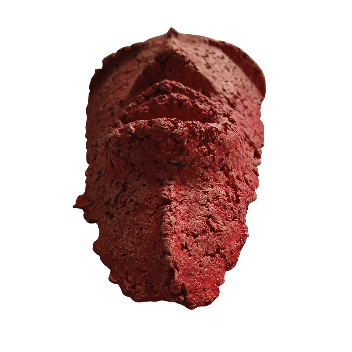 A textured, sculptural red mask sculpture with a rough, porous surface and organic, irregular shape, isolated on a plain white background.