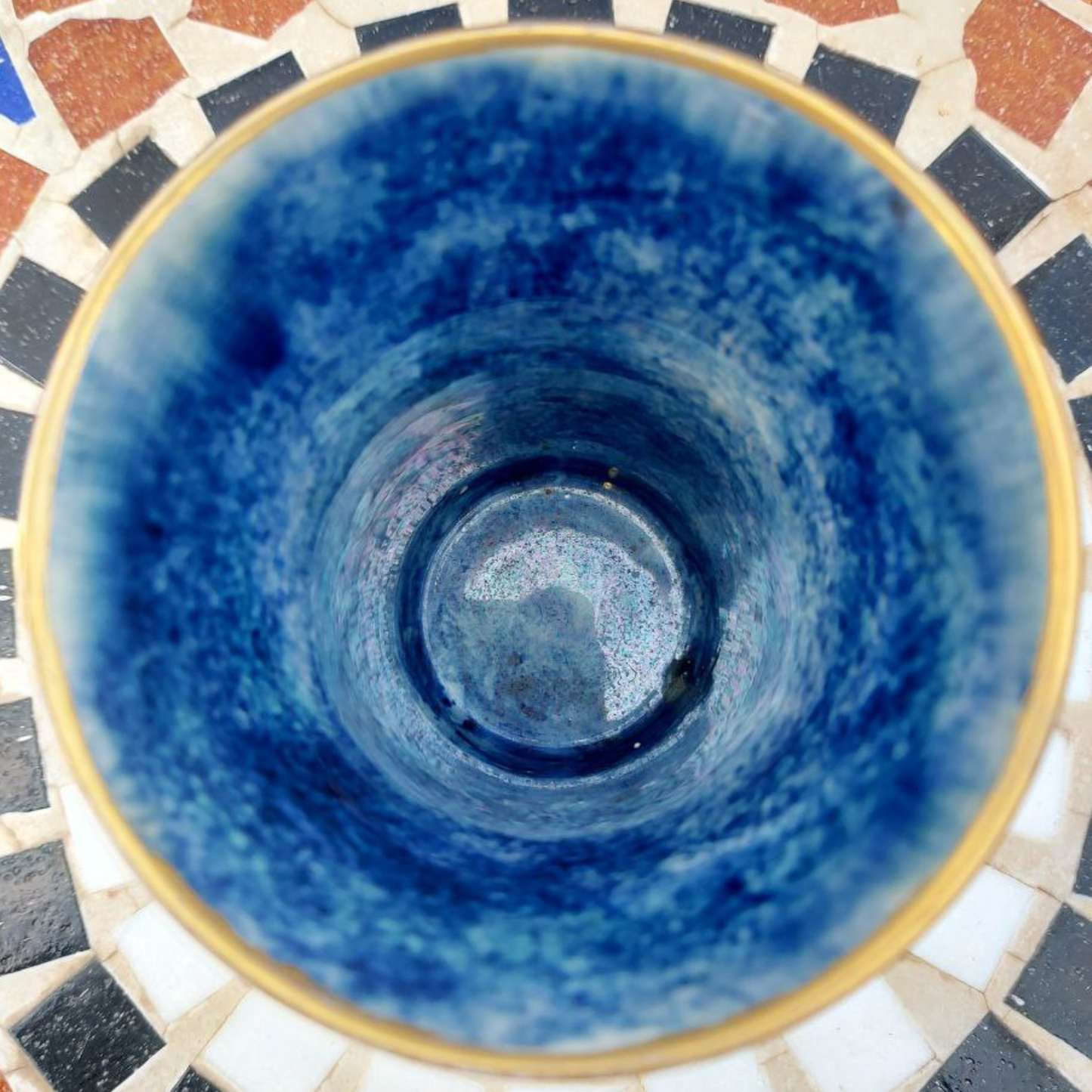 Blue ceramic vase with gold rim on a mosaic tile background