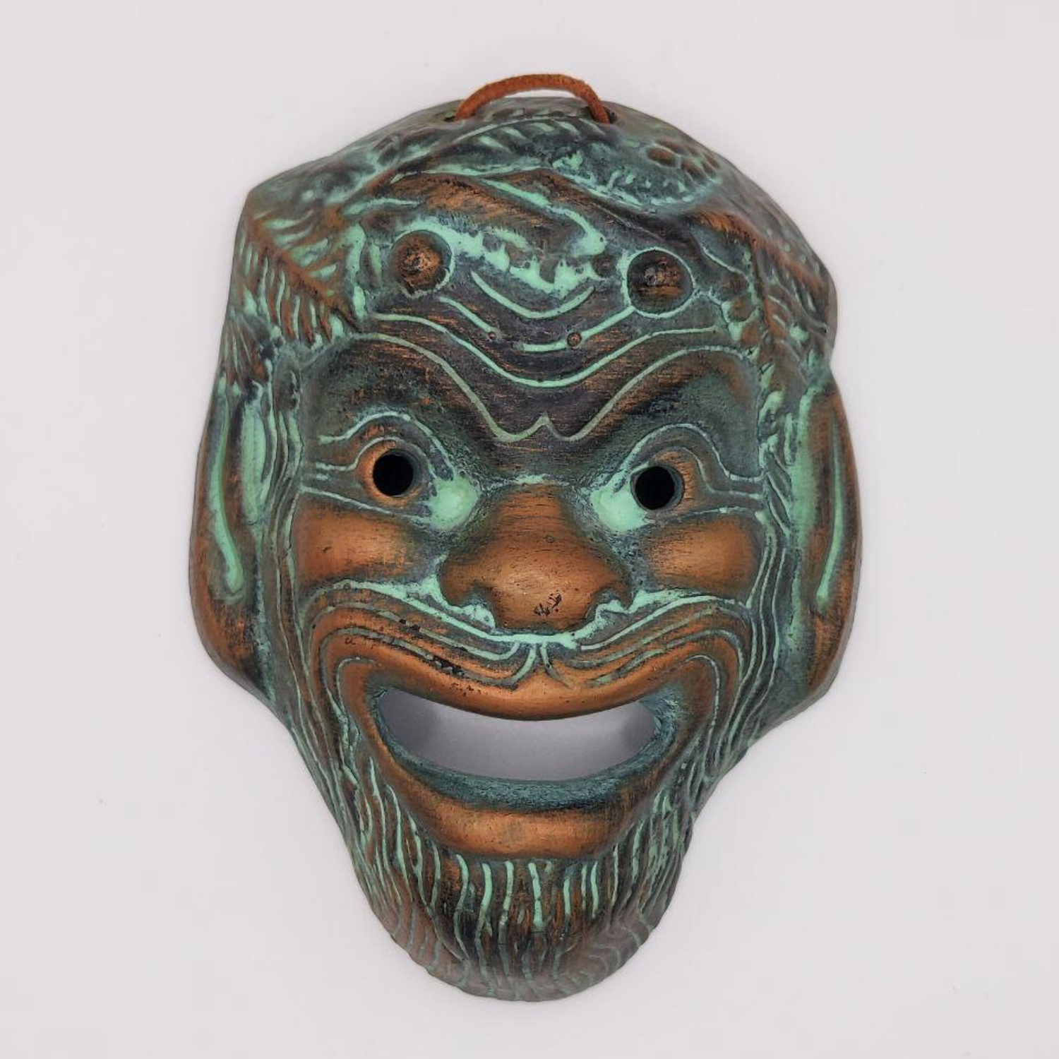 Decorative Greek theatre mask with intricate designs on a white background