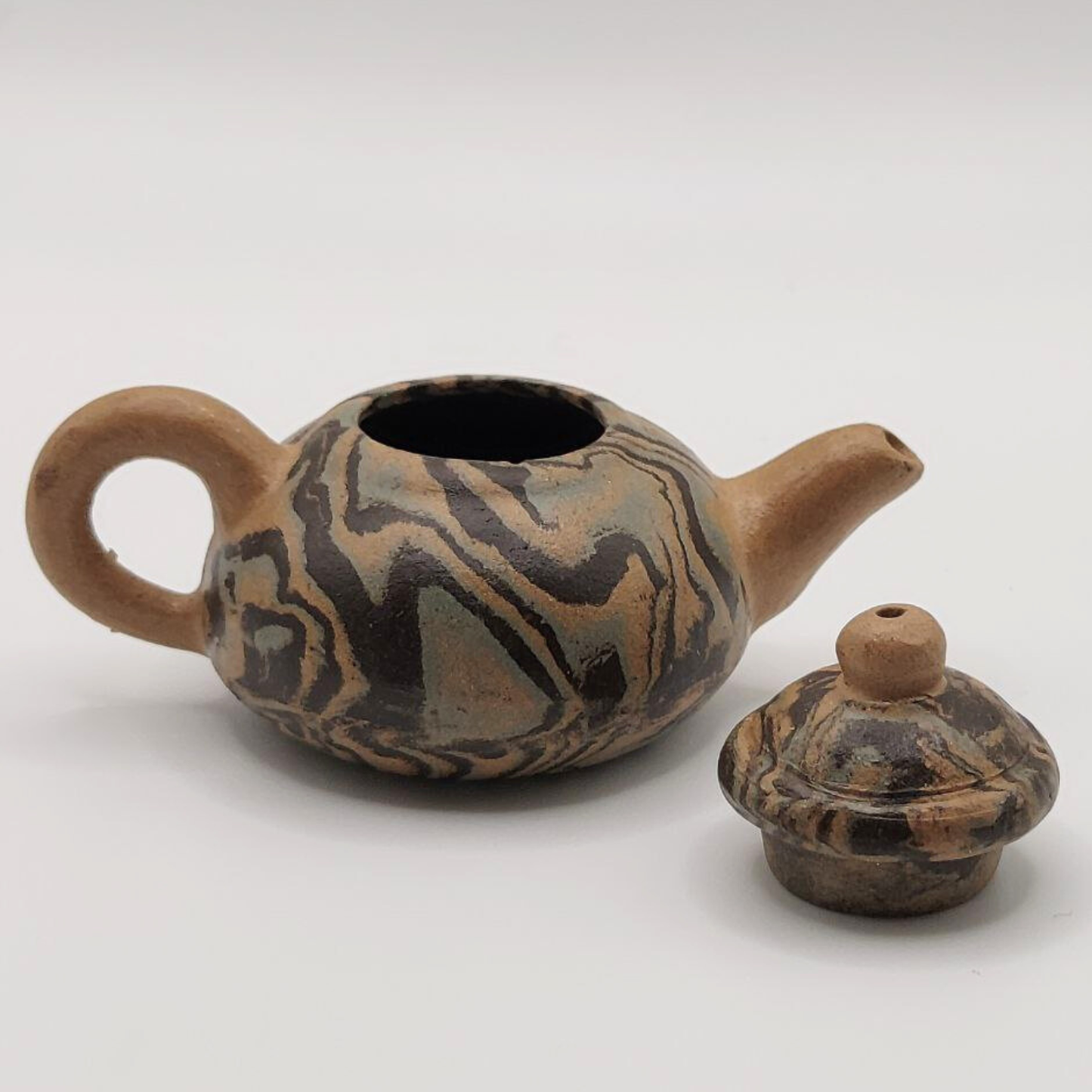 A patterned mini Chinese clay teapot on a white background