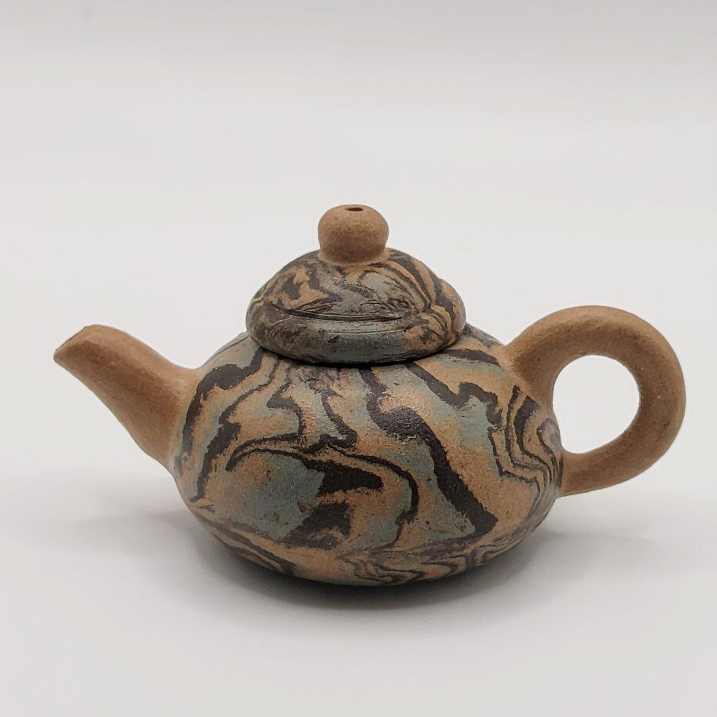 A patterned mini Chinese clay teapot on a white background