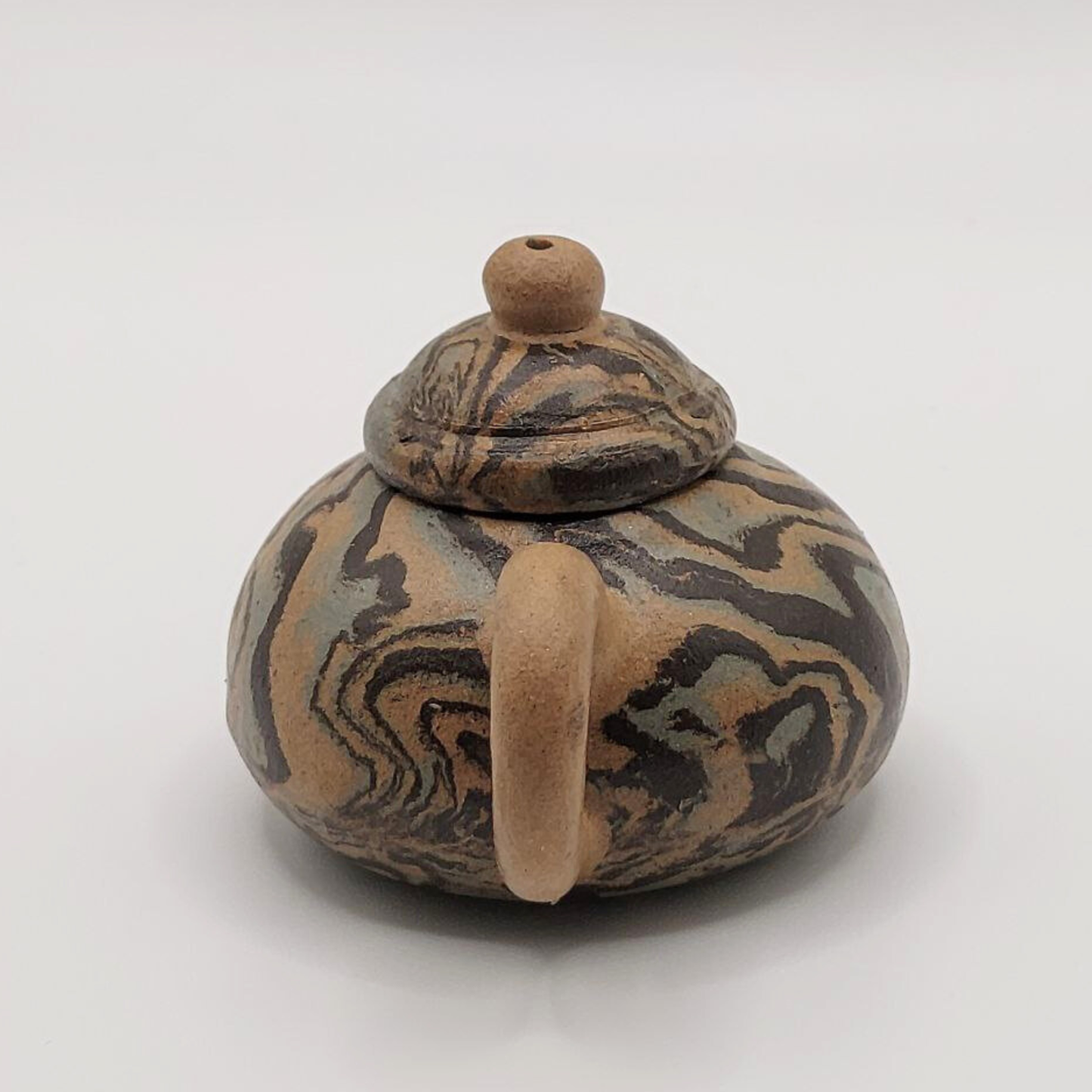 A patterned mini Chinese clay teapot on a white background