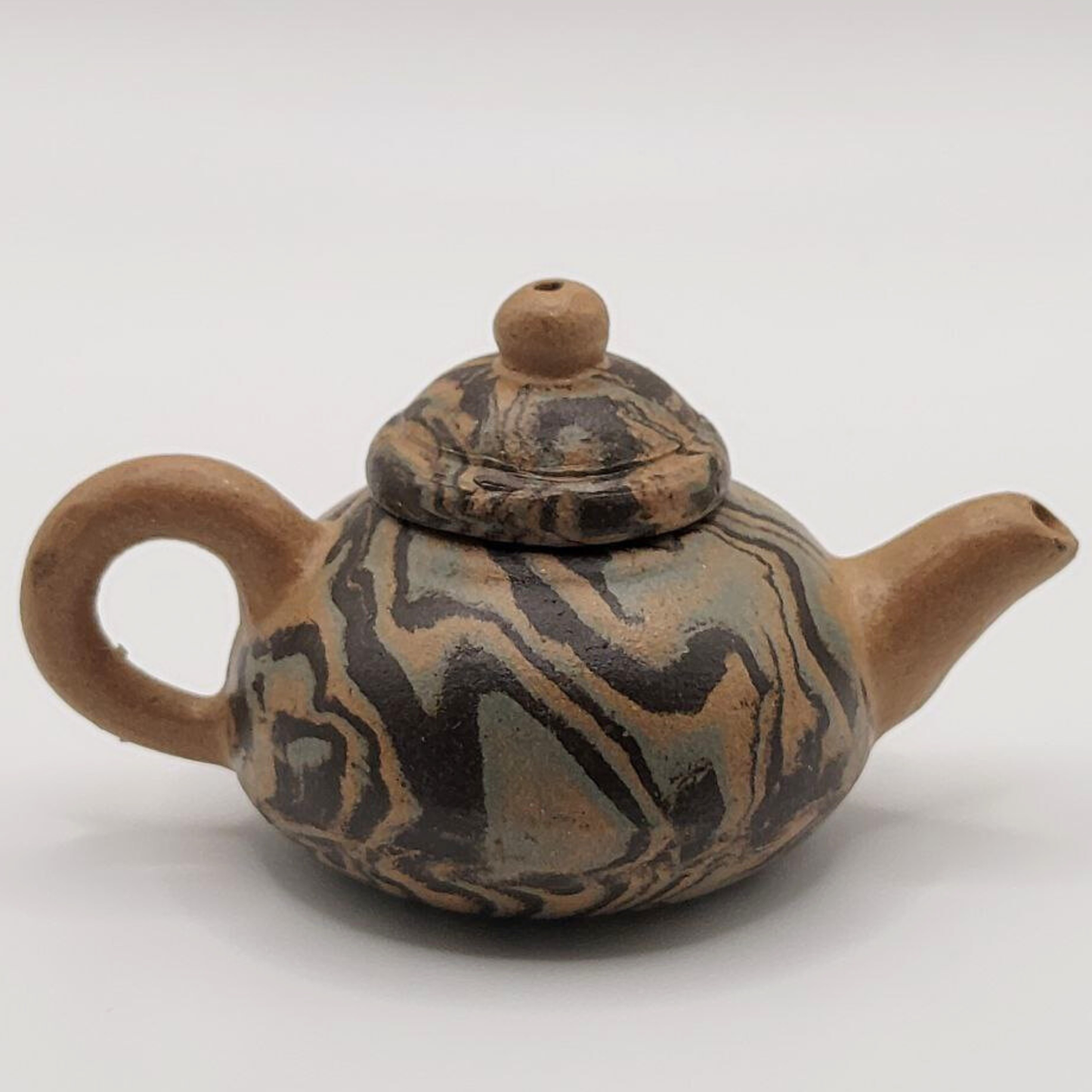 A patterned mini Chinese clay teapot on a white background