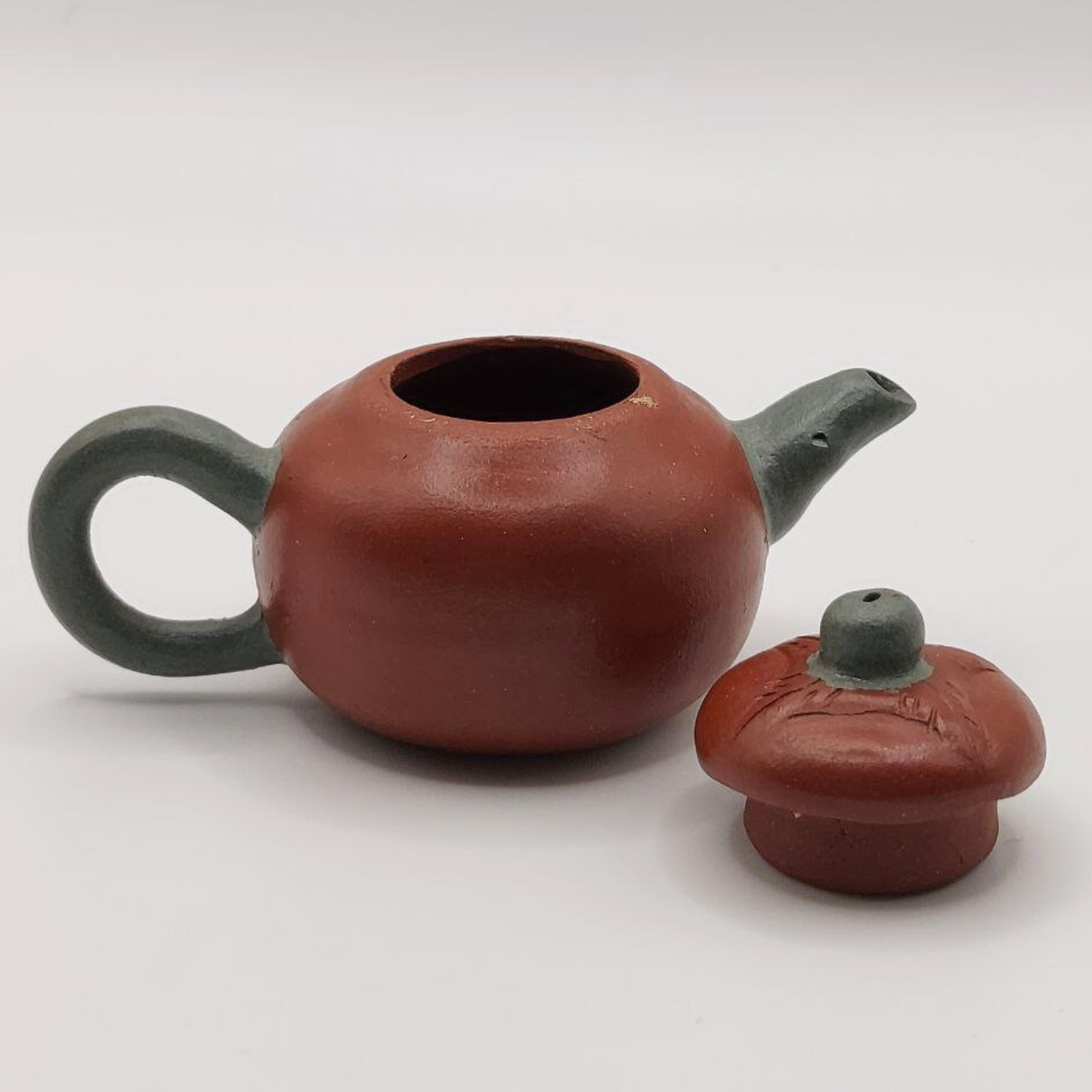 A red and green mini Chinese clay teapot on a white background