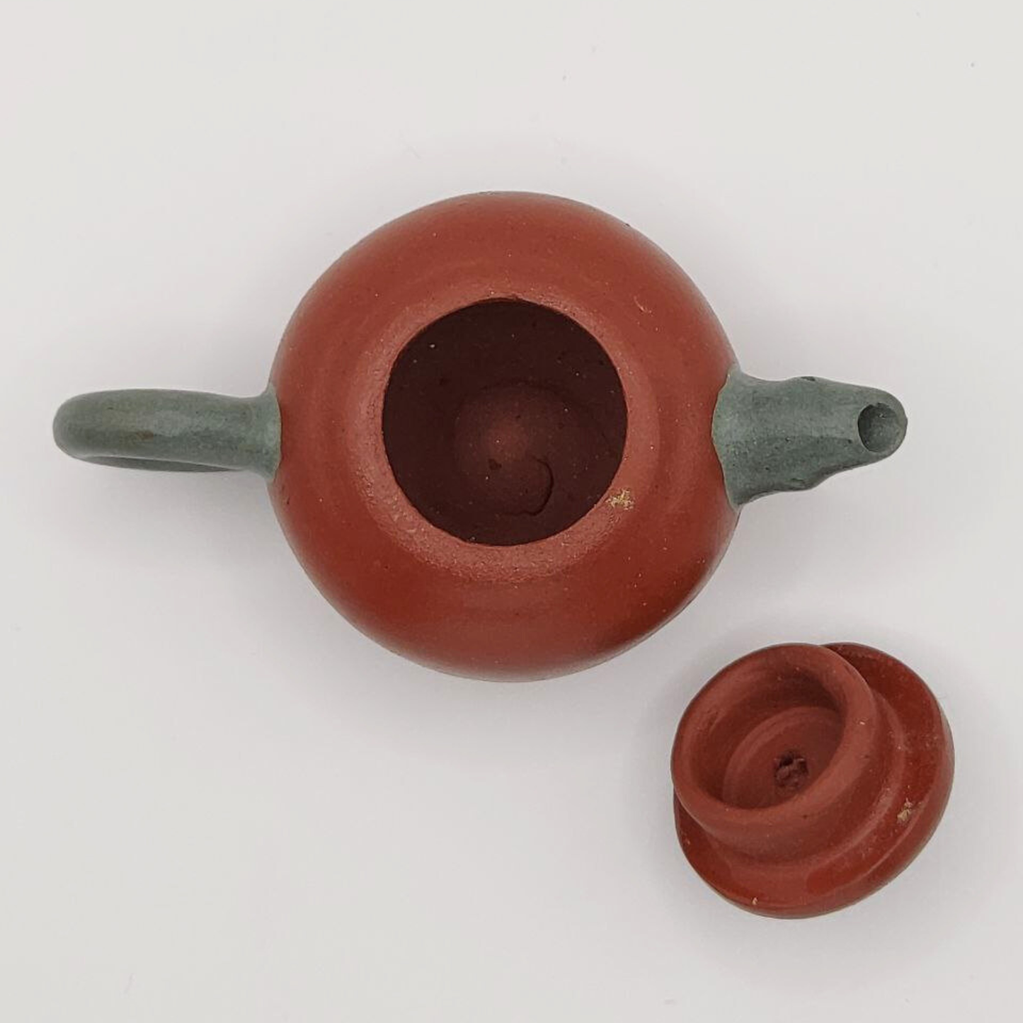 A red and green mini Chinese clay teapot on a white background