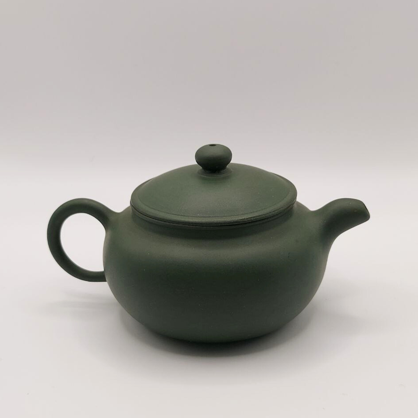 A green mini Chinese clay teapot on a white background