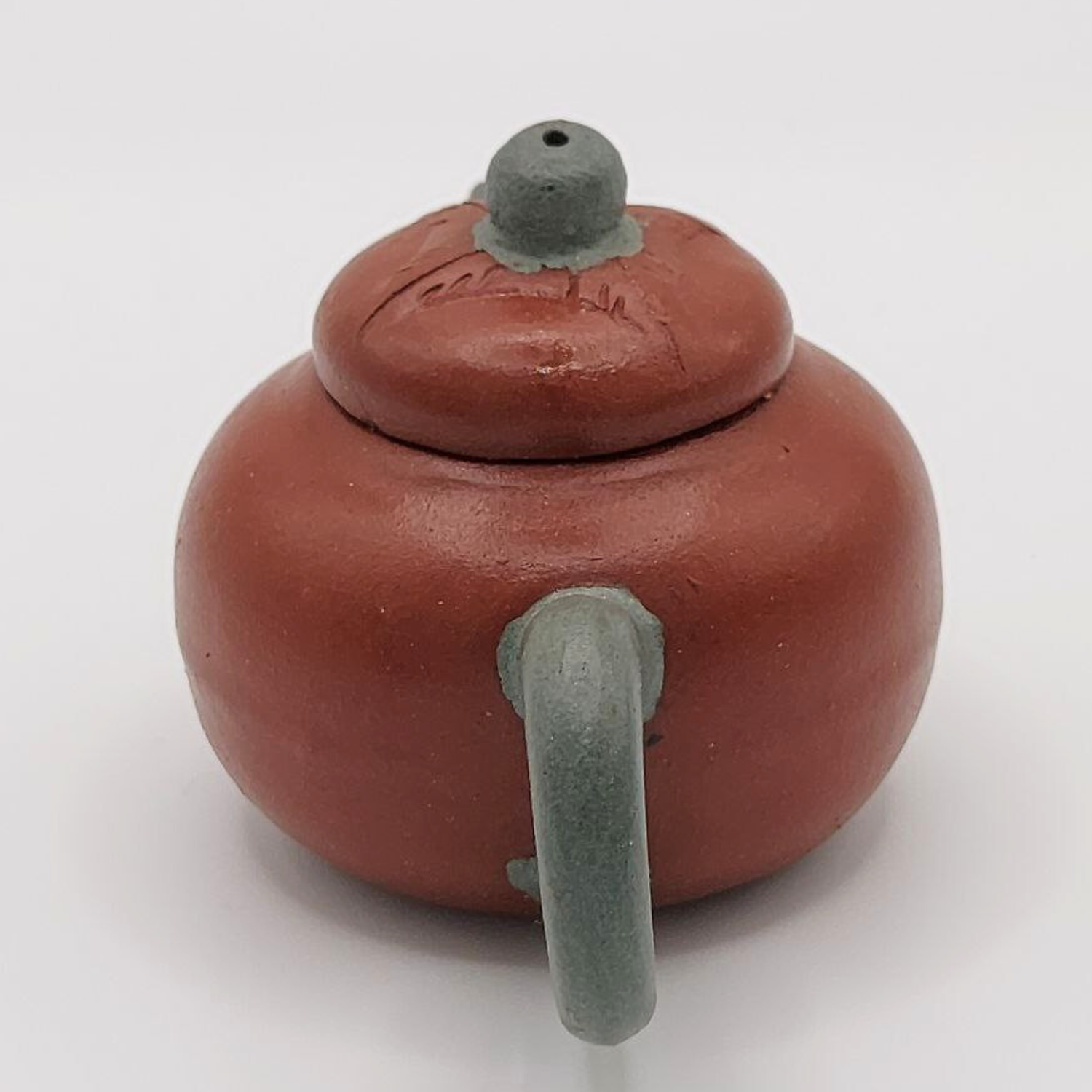 A red and green mini Chinese clay teapot on a white background