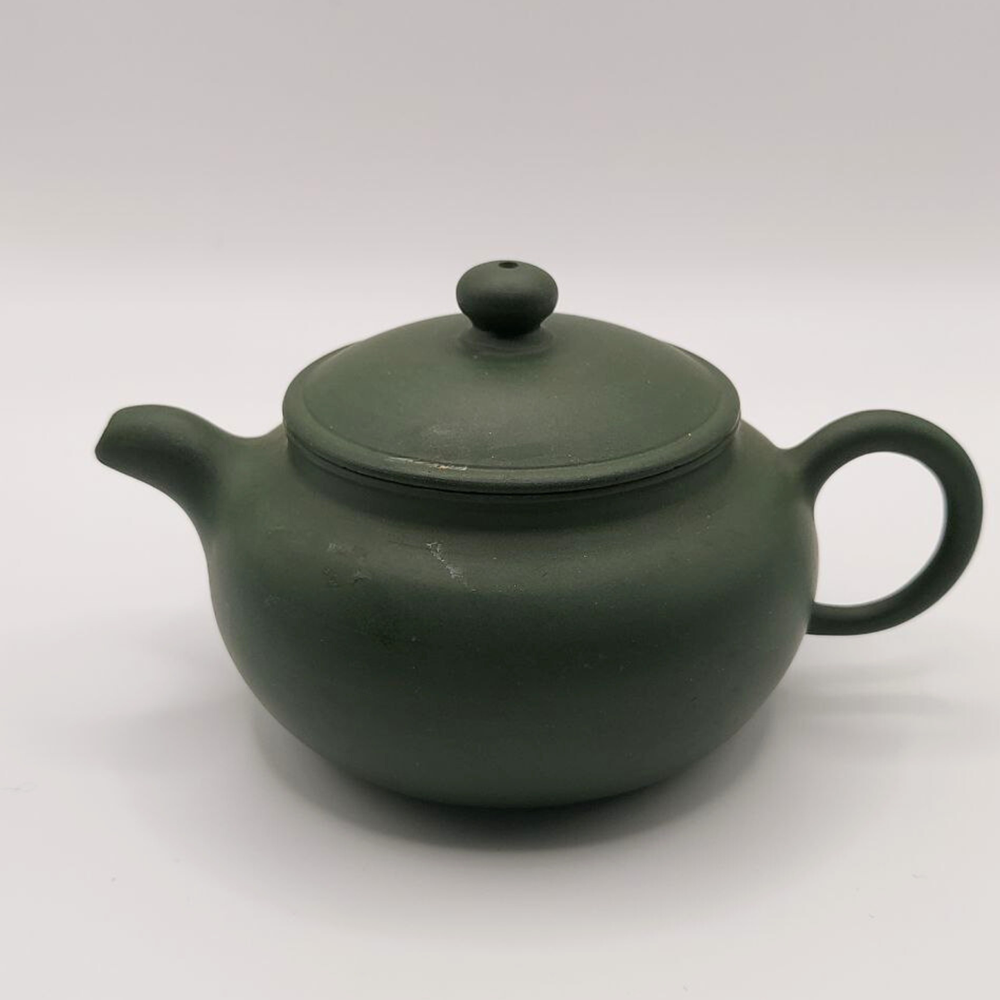 A green mini Chinese clay teapot on a white background