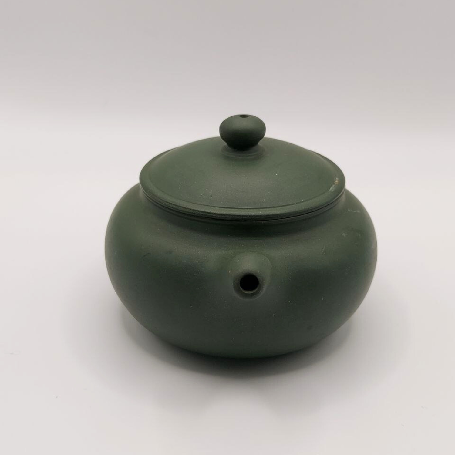 A green mini Chinese clay teapot on a white background