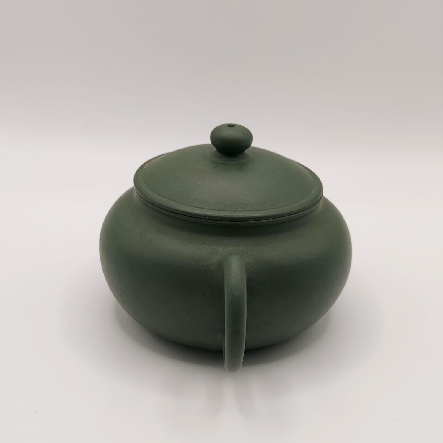 A green mini Chinese clay teapot on a white background