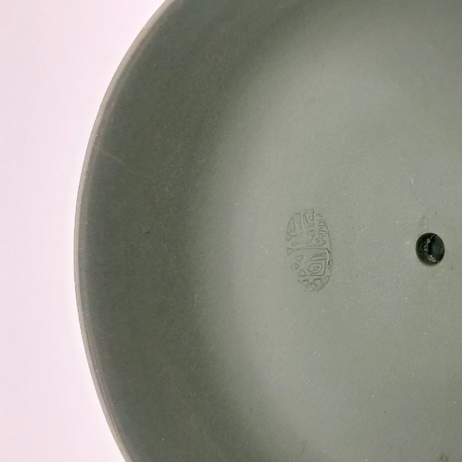 A green mini Chinese clay teapot lid on a white background