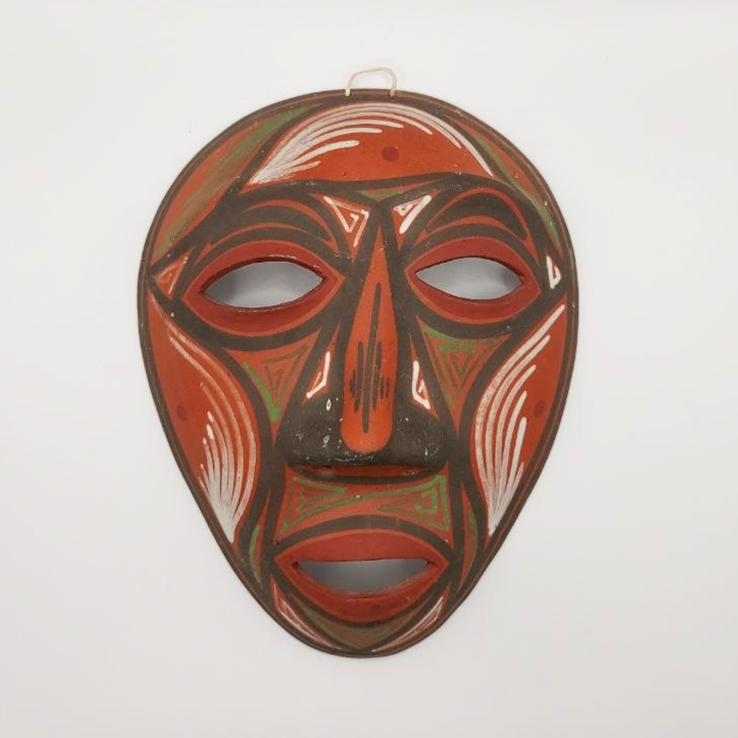 Traditional terracotta mask with red and brown colours on a white background