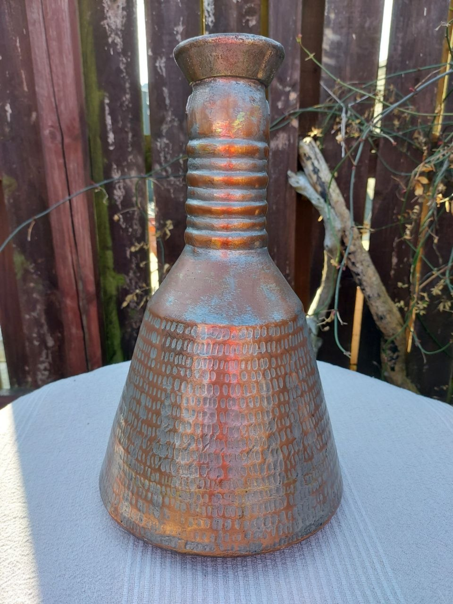 Rustic water jug with textured surface on a light surface with a wooden background