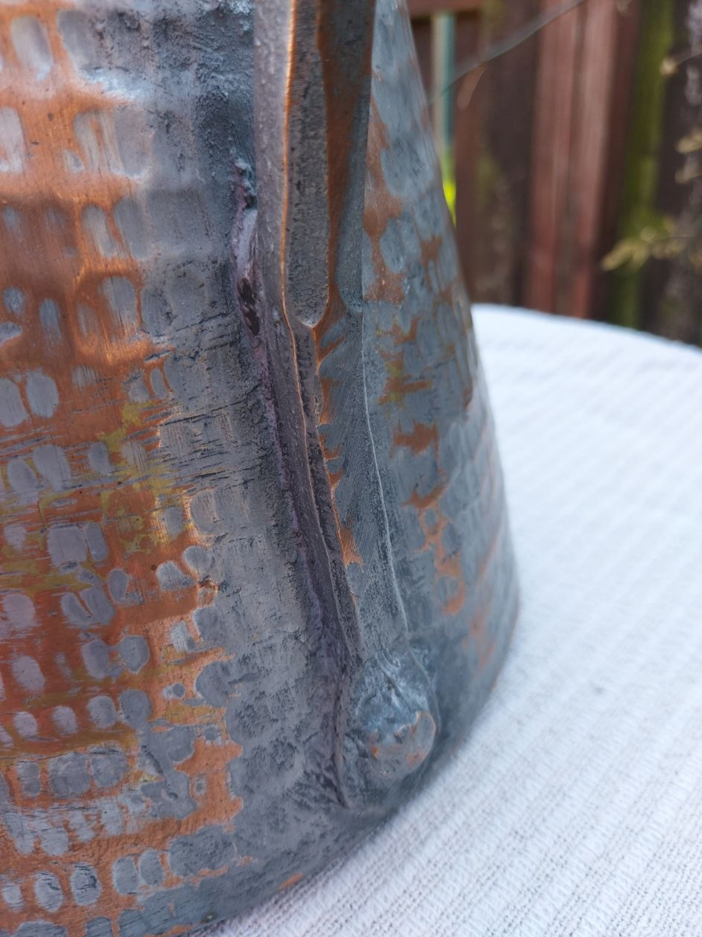 Close-up of a textured metal object on a white surface with a blurred background